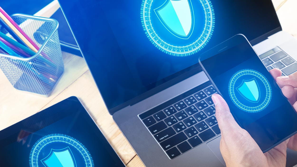 Businessman Using Smart phone to control Cyber Security with laptop and tablet.